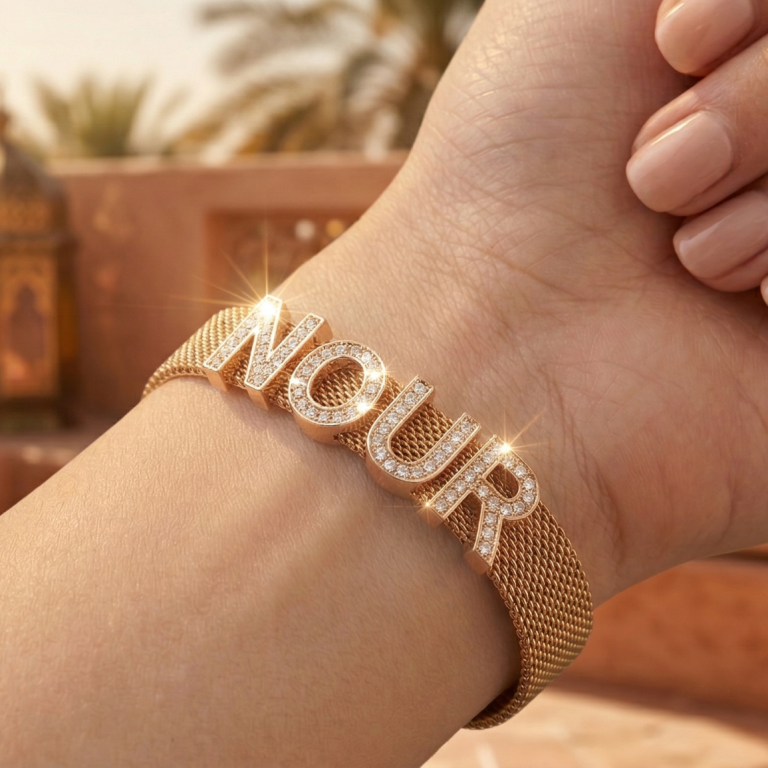 Bracelet personnalisé prénom Nour en maille milanaise dorée porté au poignet collection Aura Rêve Étoilé