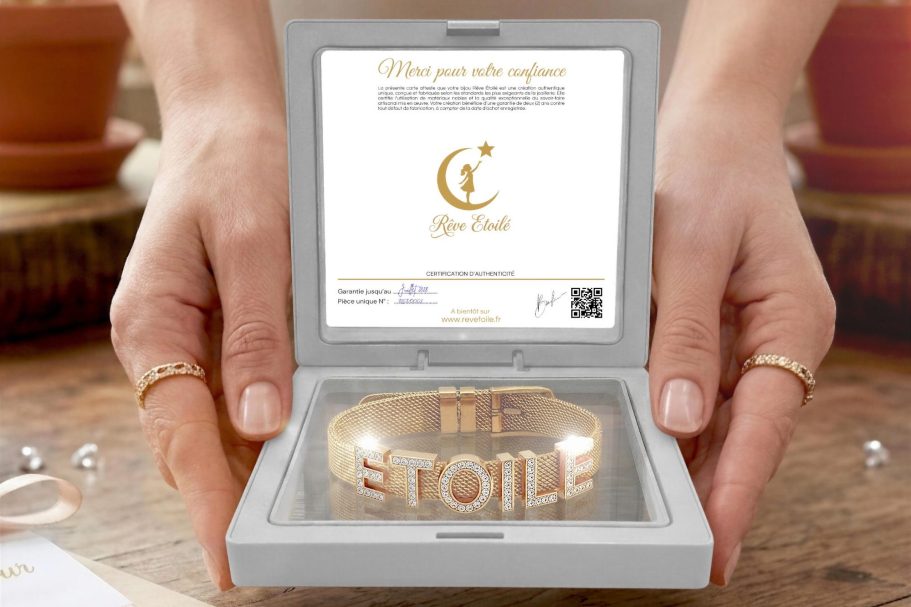 Coffret cadeau Rêve Étoilé ouvert présentant un bracelet personnalisé en maille milanaise dorée avec des lettres coulissantes en strass, ten