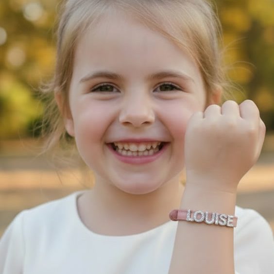Avis client Rêve Étoilé avec une petite fille souriante portant un bracelet personnalisé en cuir rose au prénom de Louise