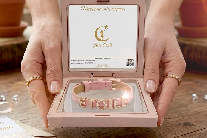 Coffret cadeau Rêve Étoilé ouvert dévoilant un bracelet personnalisé en cuir véritable rose poudré avec des lettres coulissantes en strass, 
